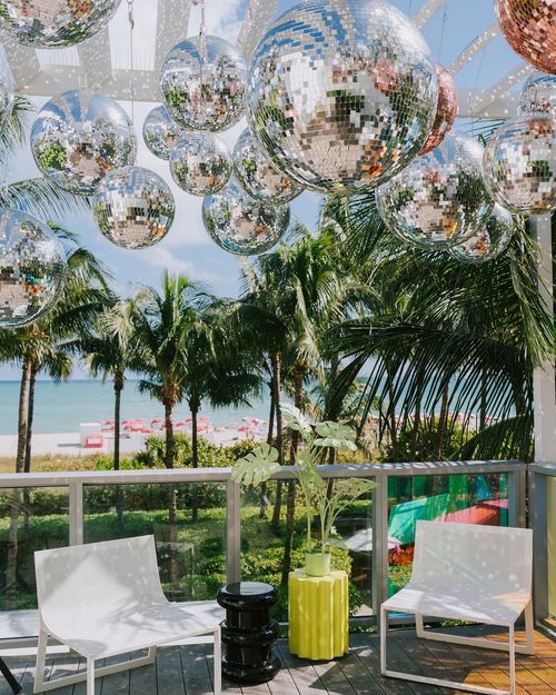 A creative image from an art exhibit with disco balls and palm trees. Its a beautiful day