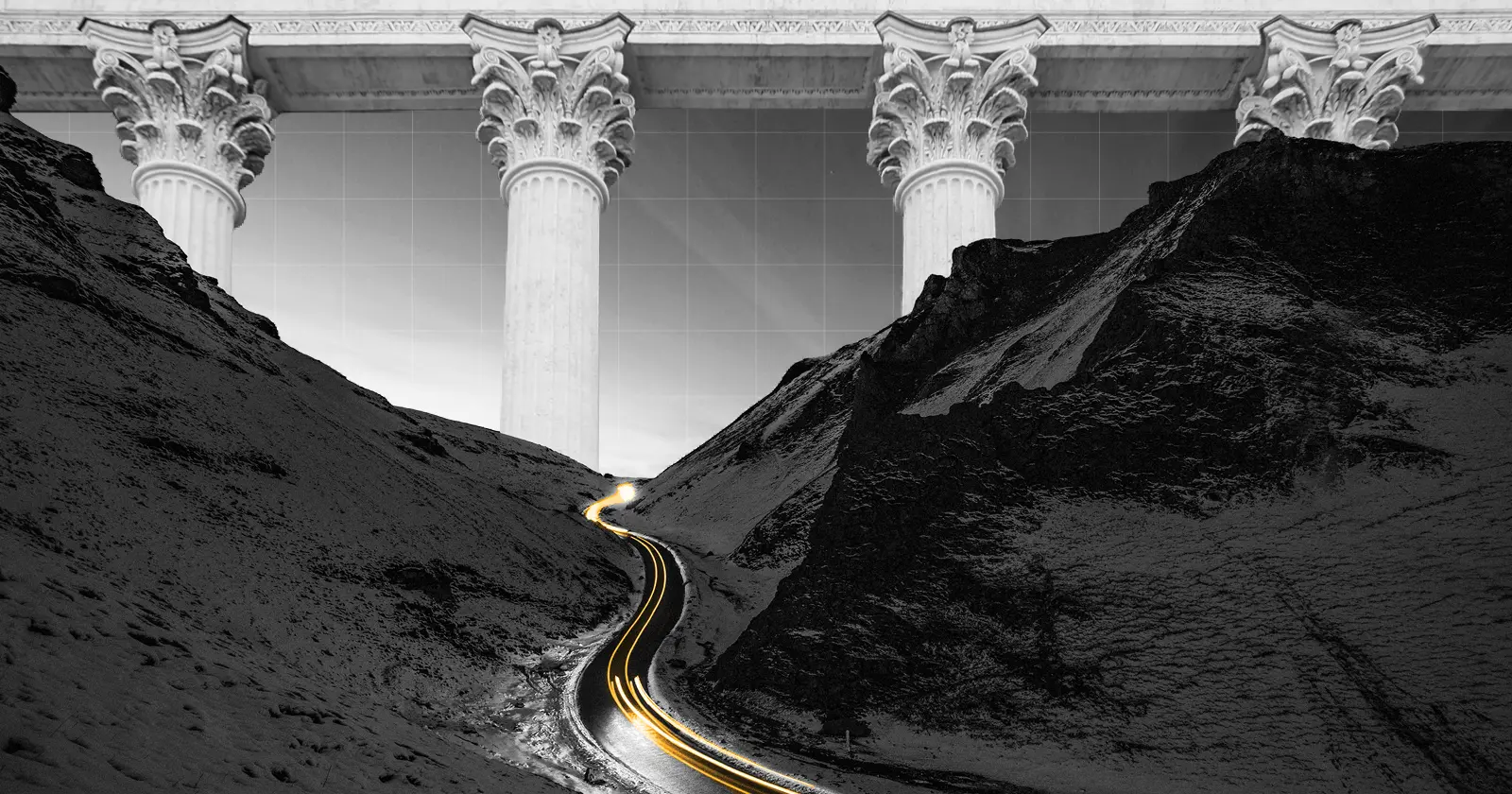 A road running through a mountain pass that has oversized marble columns in the background.