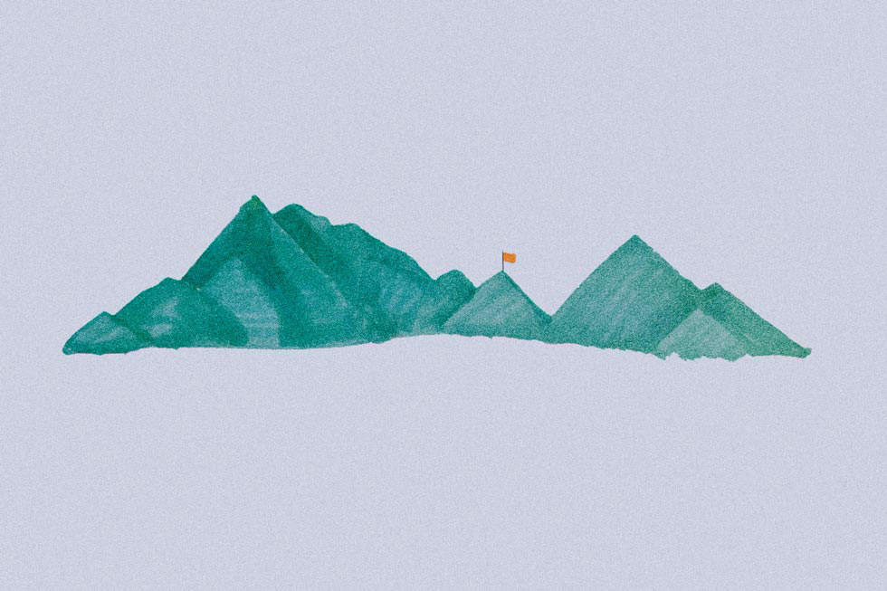 A range of mountains with an orange flag on one peak.