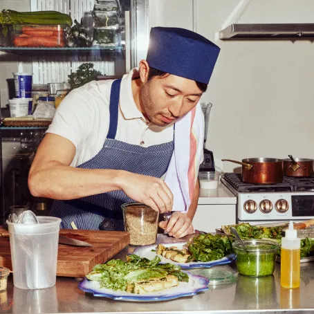 an asian chef prepares plates with cultivated meat and salad