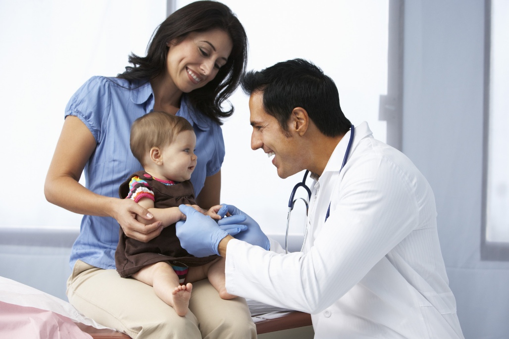 Pediatrician examining patient being held by mother