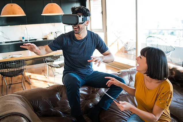 Men weraring vr glases sitting on a couch and a woman laughing