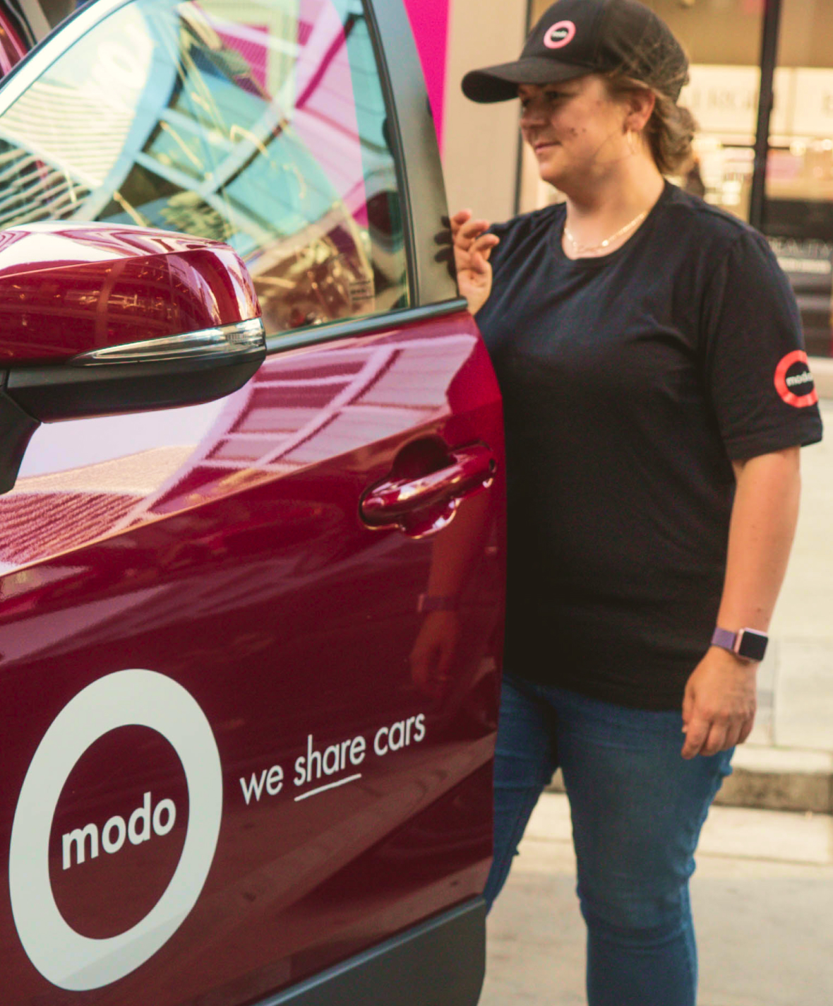 A photo of a person standing at the open door of a Modo vehicle