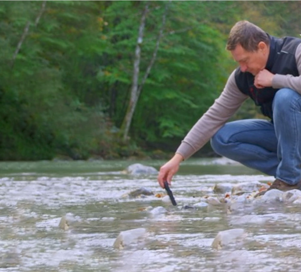A man taking water samples from a river.