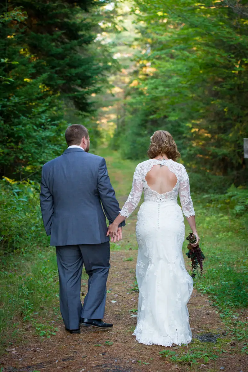 A bride and groom walk down the nature trails at the Lake Clear Lodge & Resort.