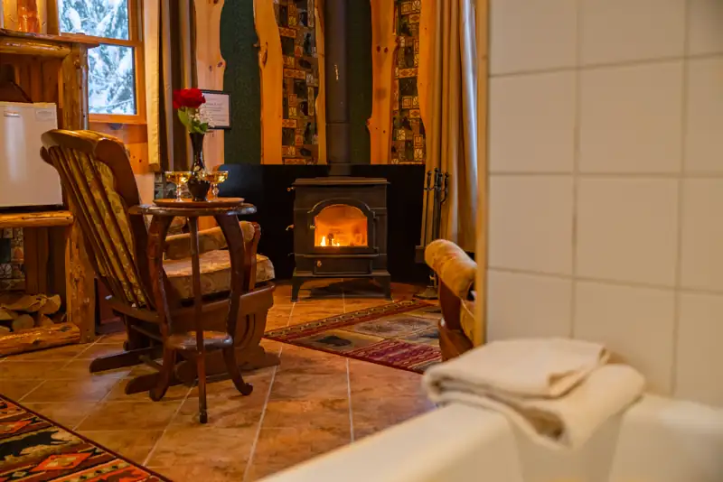 Guide's Cabin interior with champagne glasses, roses, wood-burning fireplace, and jetted tub.