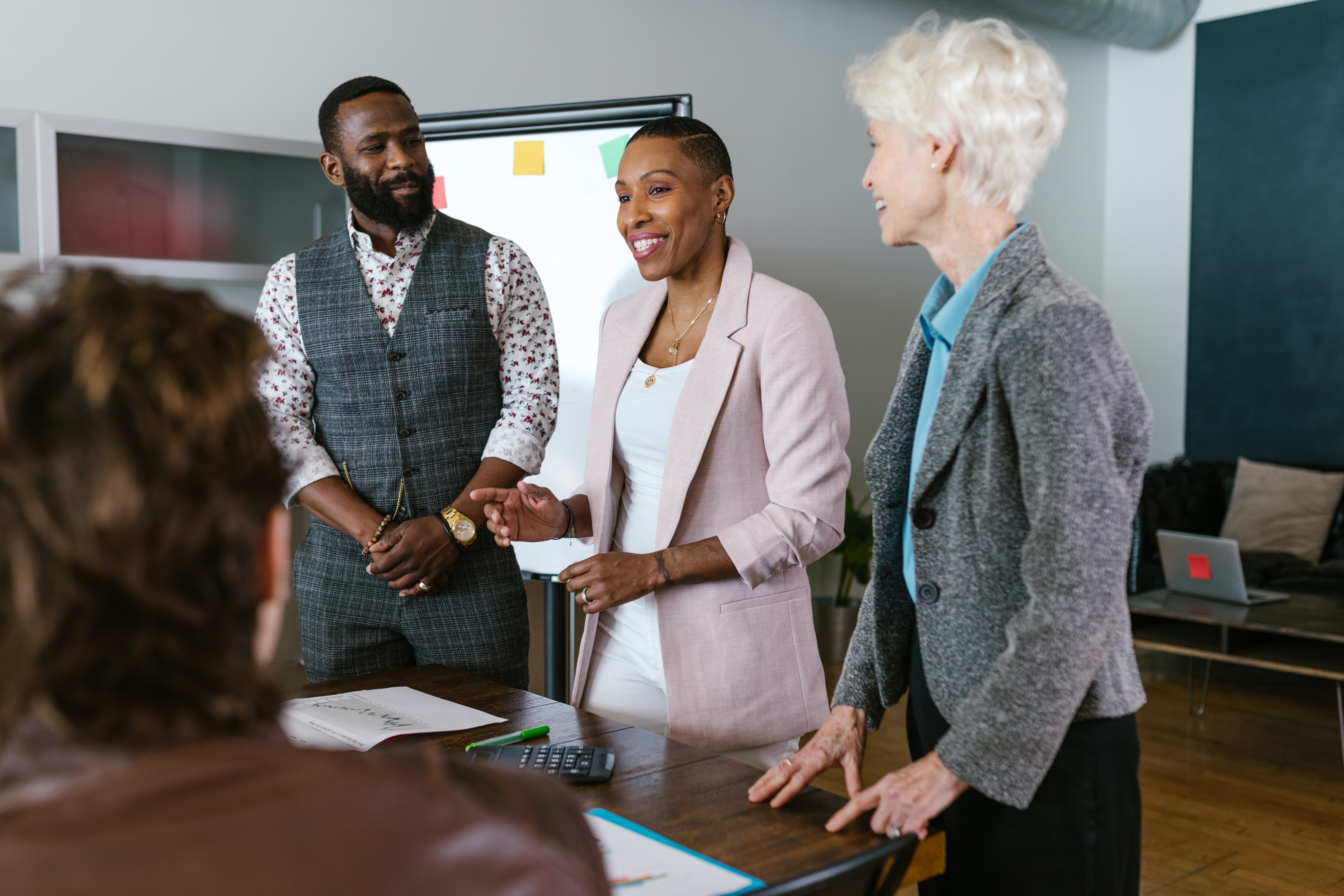 An image of a man and two women in business wears having a conversation