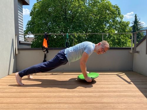 A man doing push-ups on a balance board.