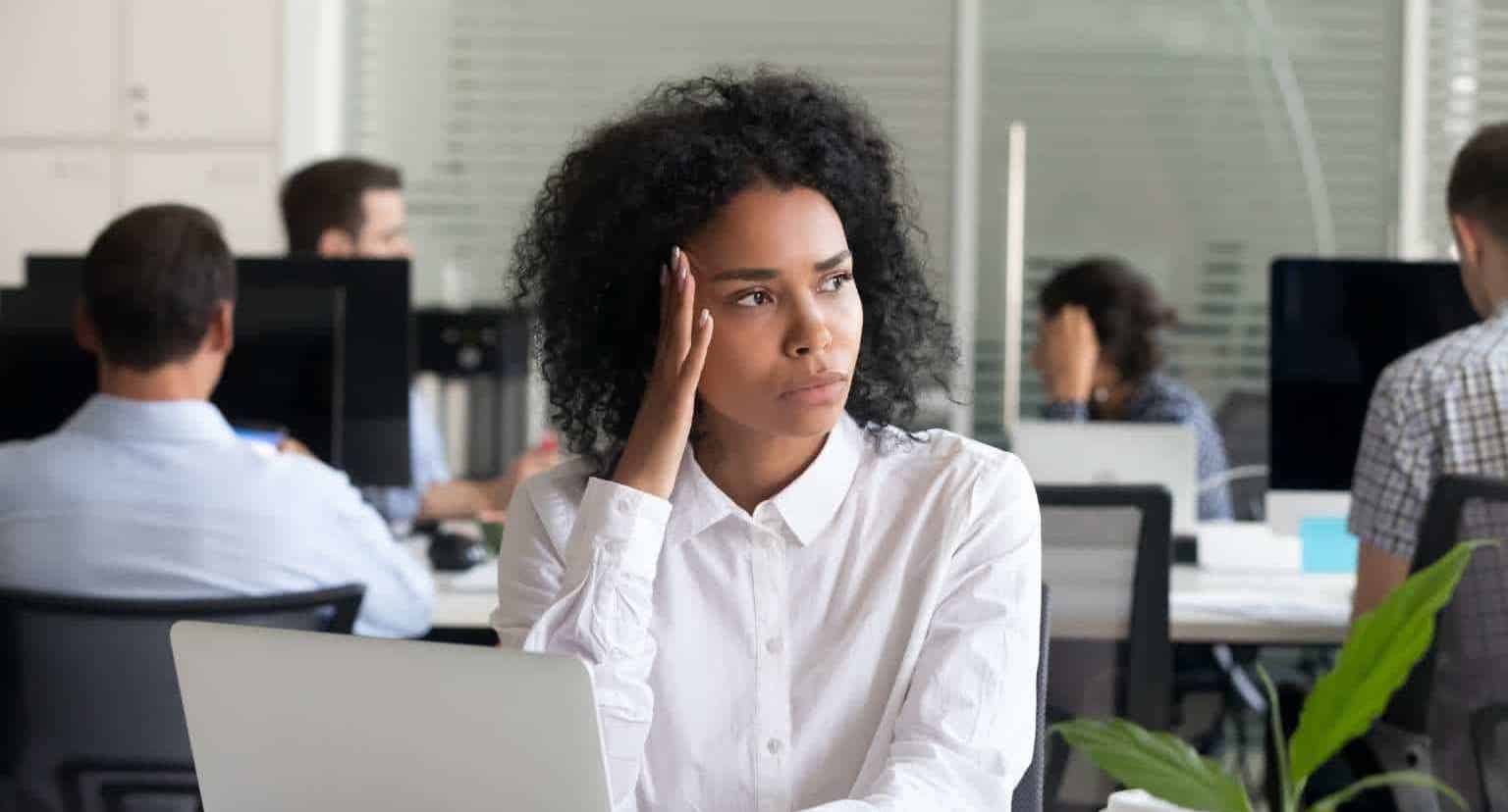 Woman in a white button down experiencing burnout in her office