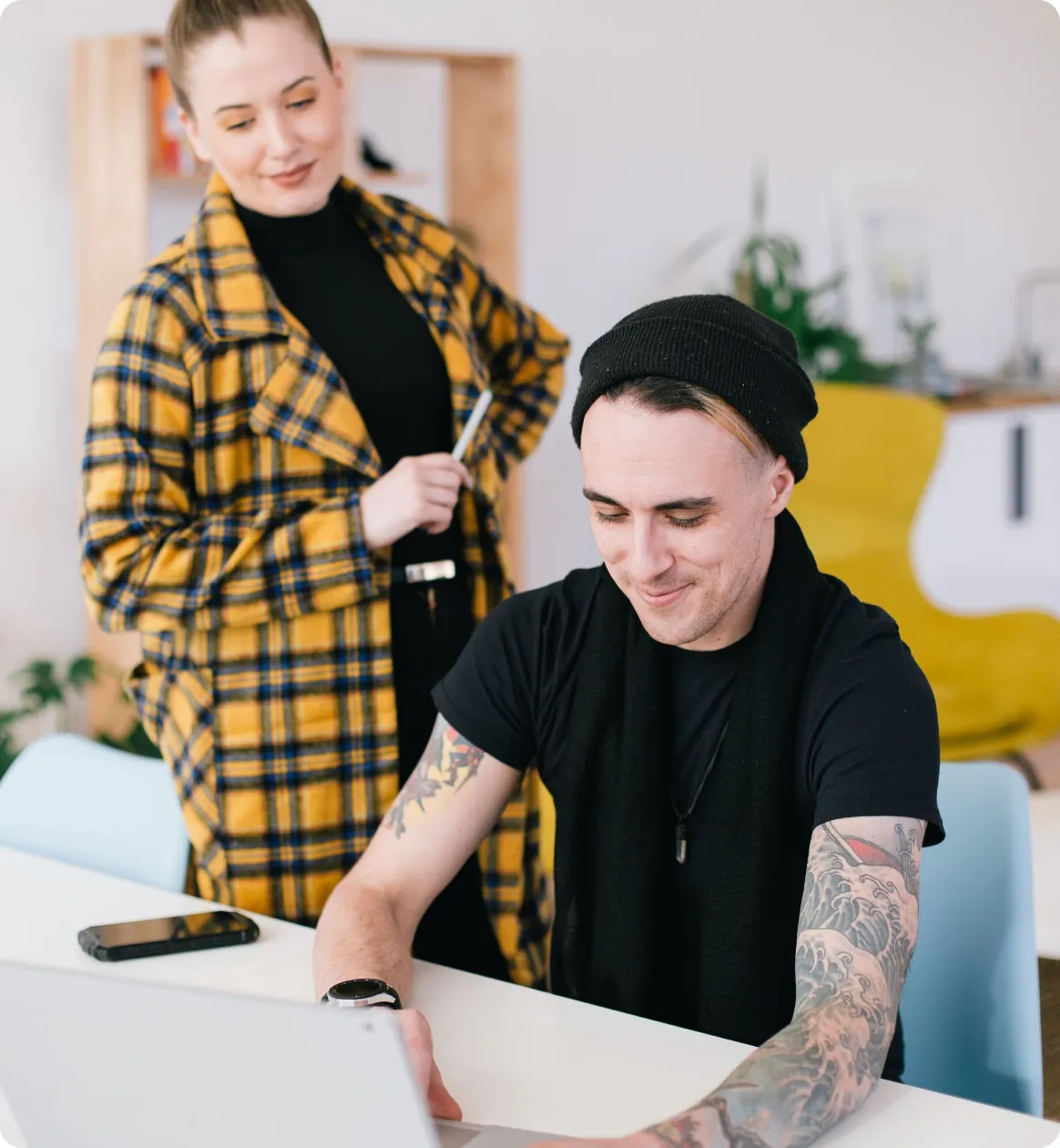 Employees with tattoos looking at computer screen together