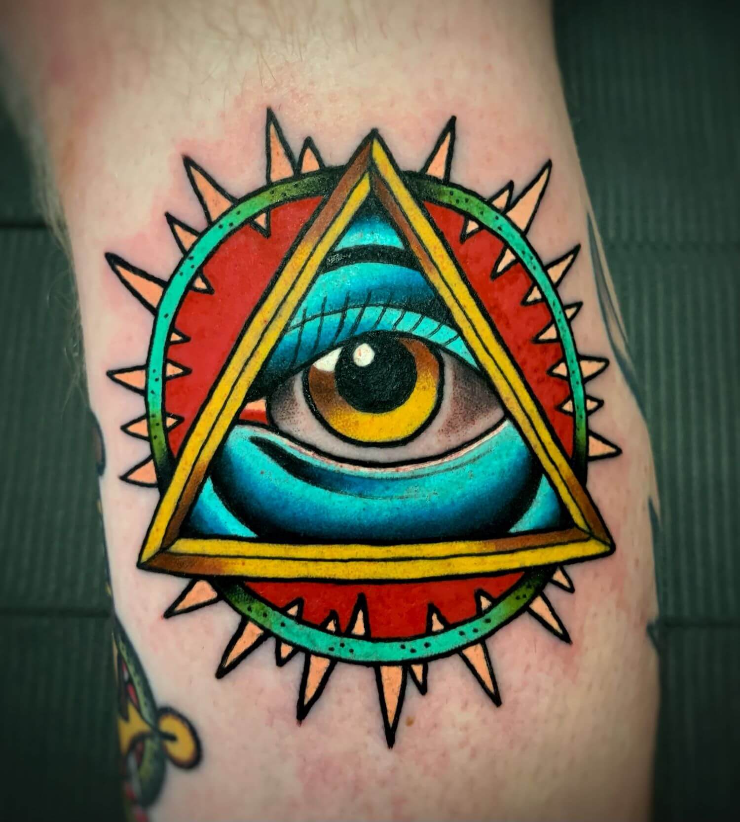 Blue All Seeing Eye with golden iris by Gilbert Gonzalez at Saints and Sinners Tattoo.