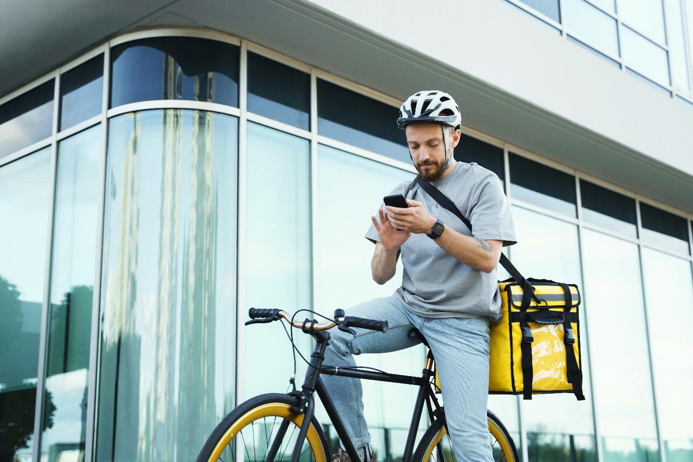 A person on a bicycle looking at his phoneDescription automatically generated with medium confidence