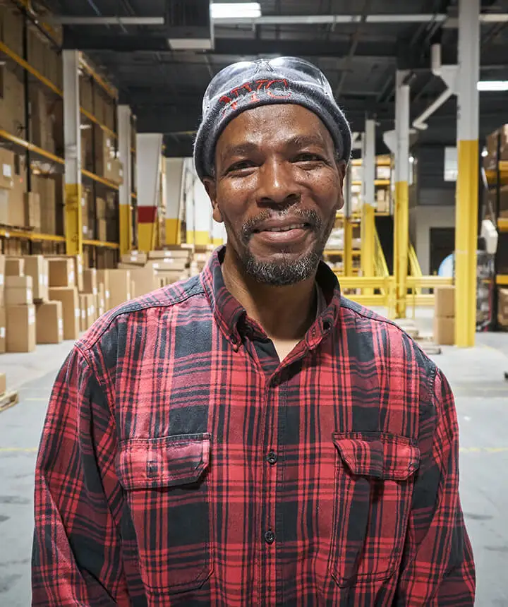 Portrait of a black man wearing a red plaid shirt in a warehouse
