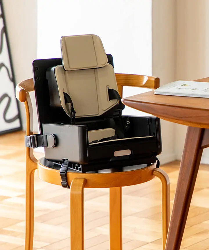 IKOU child's chair resting on a kitchen chair next to a dining table