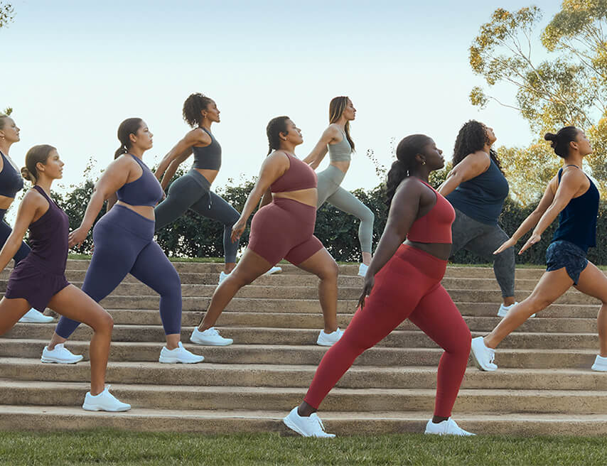 A group of diverse women doing yoga on a set of wide stairs outside
