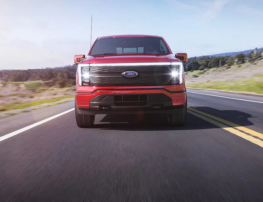 Head-on view of a red ford truck driving on an open road