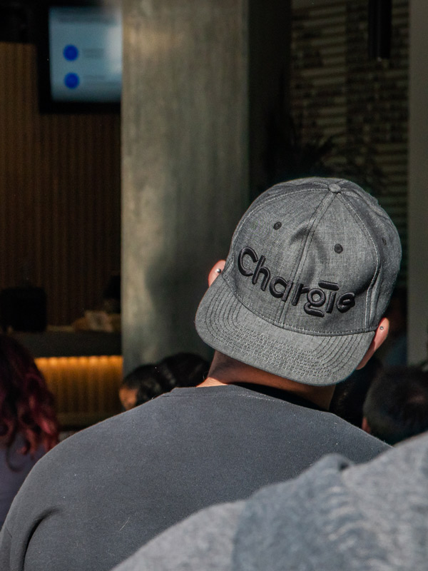 Rear view of a Chargie team member wearing a Chargie branded cap, looking at the presentation screen.