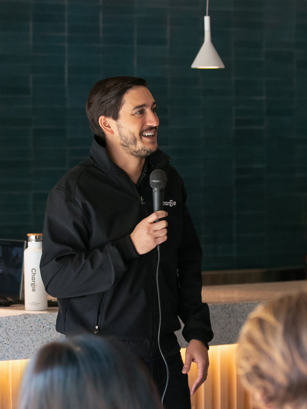 Chargie leadership team member holding a mike while speaking in front of his colleagues during presentation.