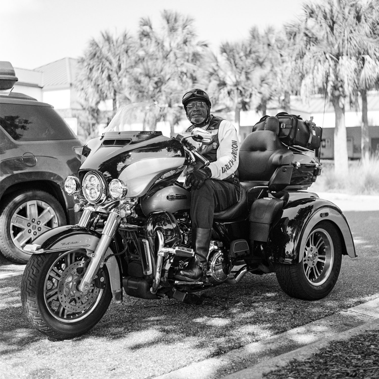 Black and white photo of a Black man sitting on his three-wheeled motorcycle. This photo is part of Imran Nuri's Advice From America photo series and book.