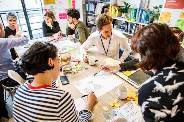 A group of people at a workshop sitting around a table and sharing their ideas.