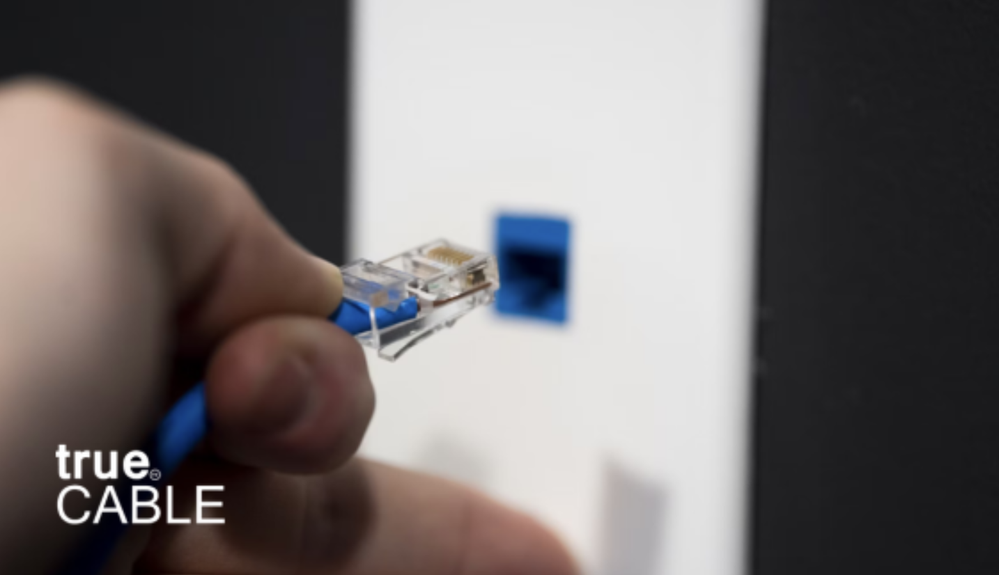 A hand plugging an ethernet cable into a port