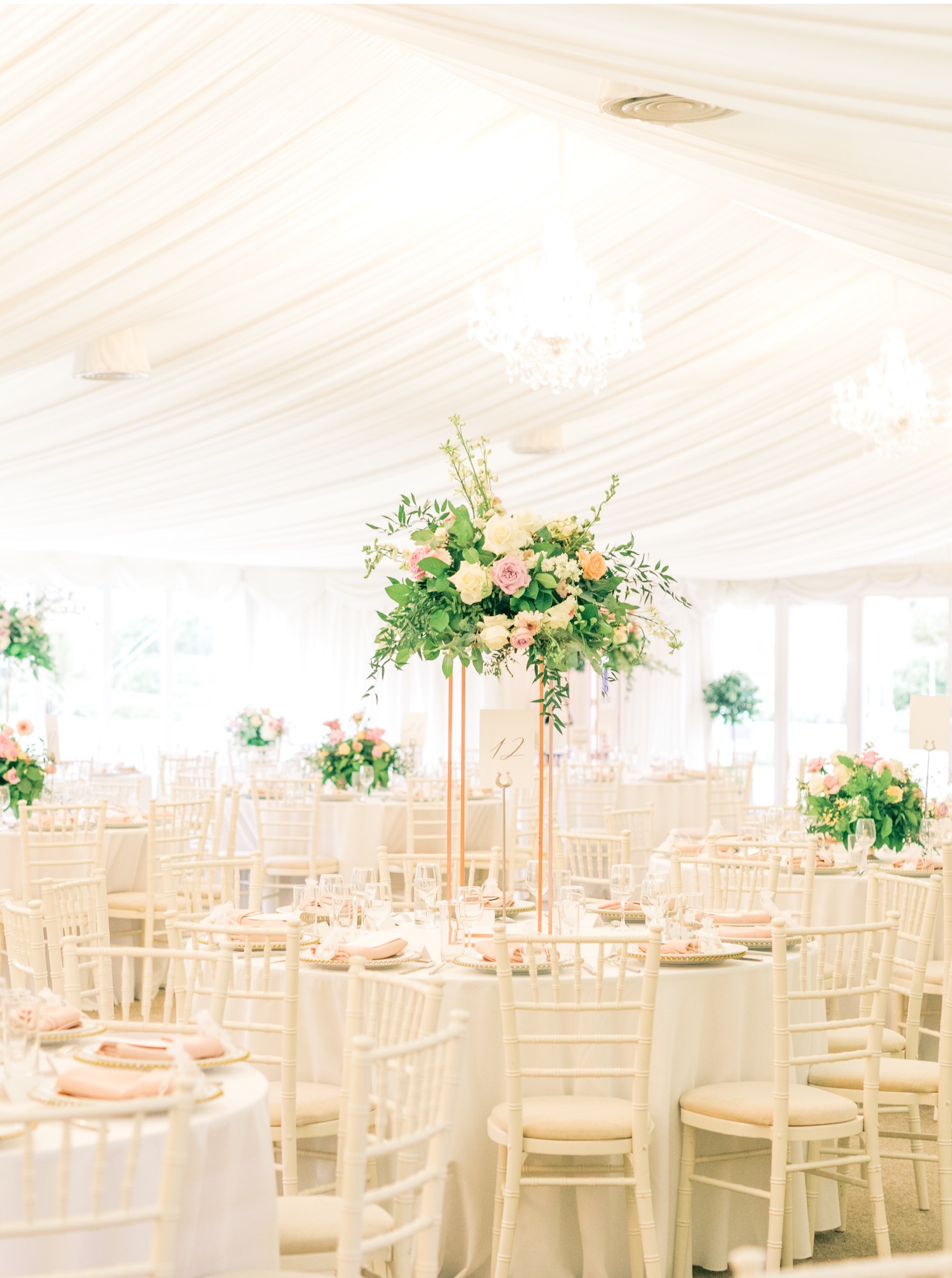 Beautiful and contemporary wedding reception in a light-filled pavilion, adorned with abundant florals and elegant cutlery and glassware at North Mymms Park