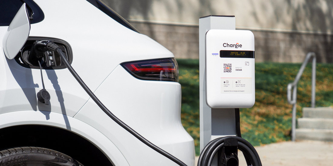 A level 2 Chargie Charger plugged into a white EV on the side of an outdoor parking lot.