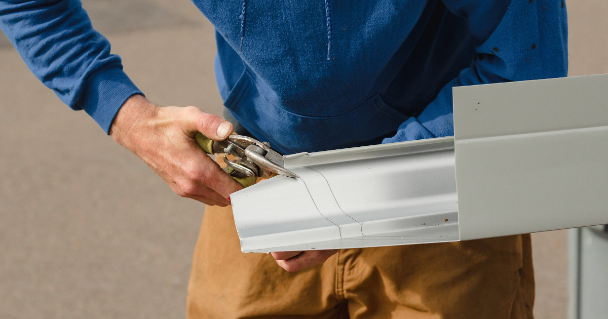 Pacific Gutter Company work cutting an aluminum gutter to fit.