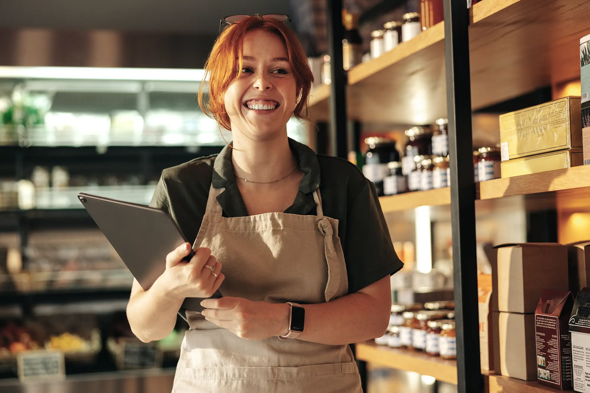 Supermarket employee with apron holds tablet running the ReAct app for retail.