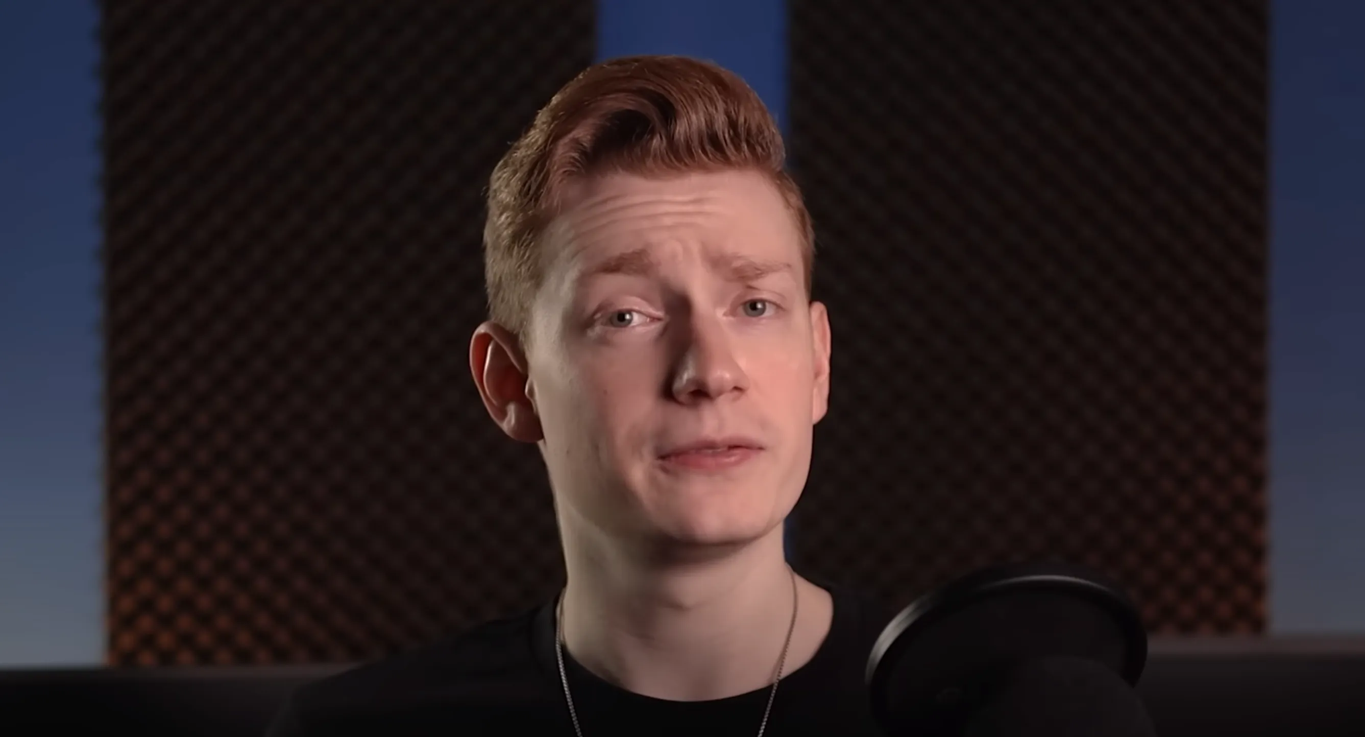 Redhead man sitting in room with sound barrier in front of microphone