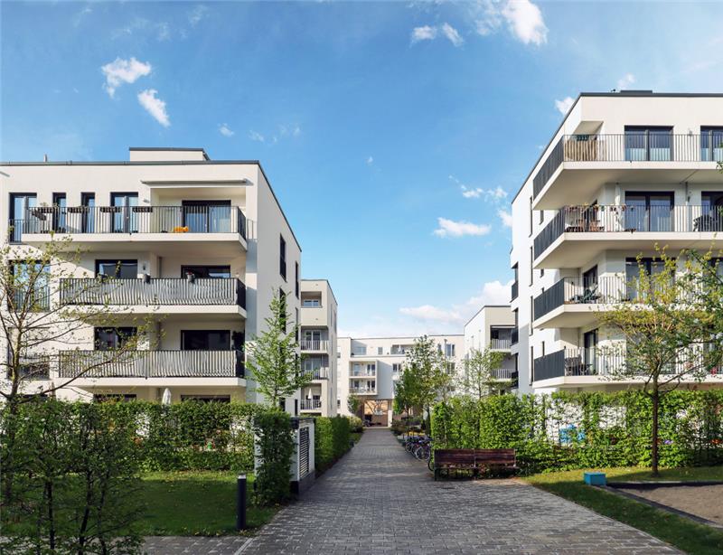 Regli Ratgeber Neubaugebiet Weiße Mehrstöckige Mehrfamilienhäuser Balkon und Garten Bäume Weg zwischen Häuser Büsche