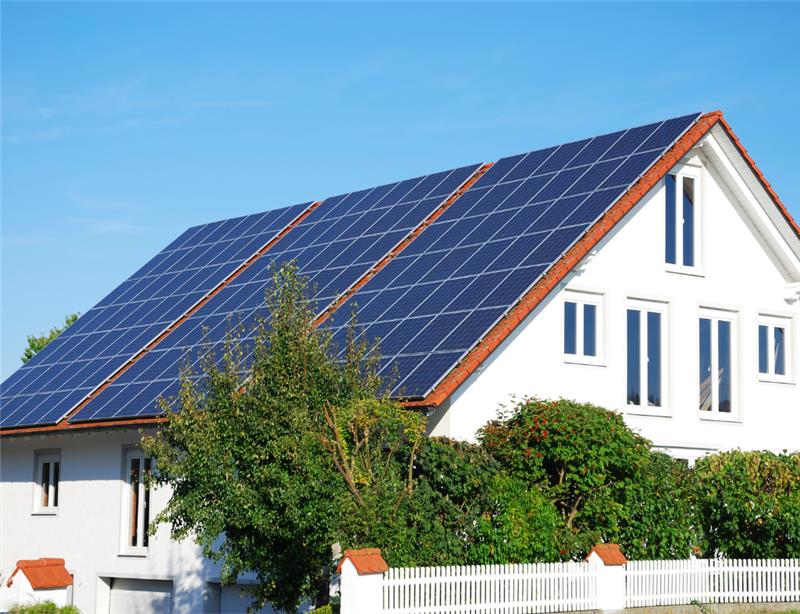 Regli Ratgeber modernes Mehrfamilienhaus mit Solarpanels auf Dach Zaun mit Hecke vor Haus