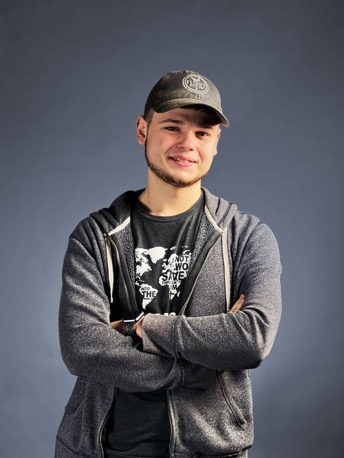 Studio Portrait of Luke Arthur standing with arms crossed smiling.