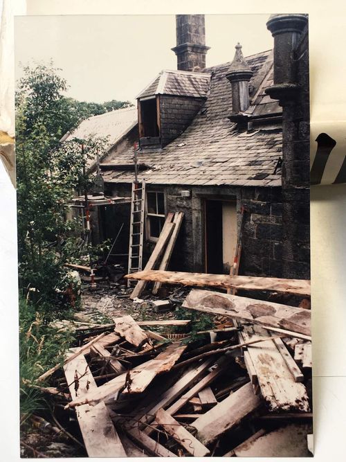 An old scanned photo of the property in disrepair taken in the 1980's, broken roof and rubble