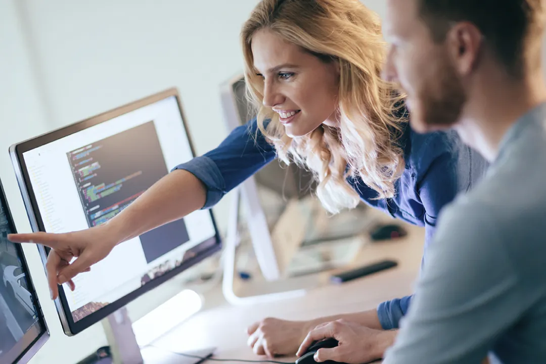 a man and a woman looking at a computer screen and pointing