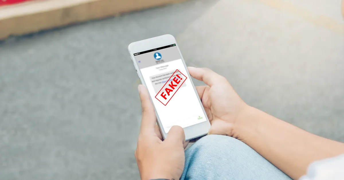 Person holding smartphone with display showing "scam" in bold letters.