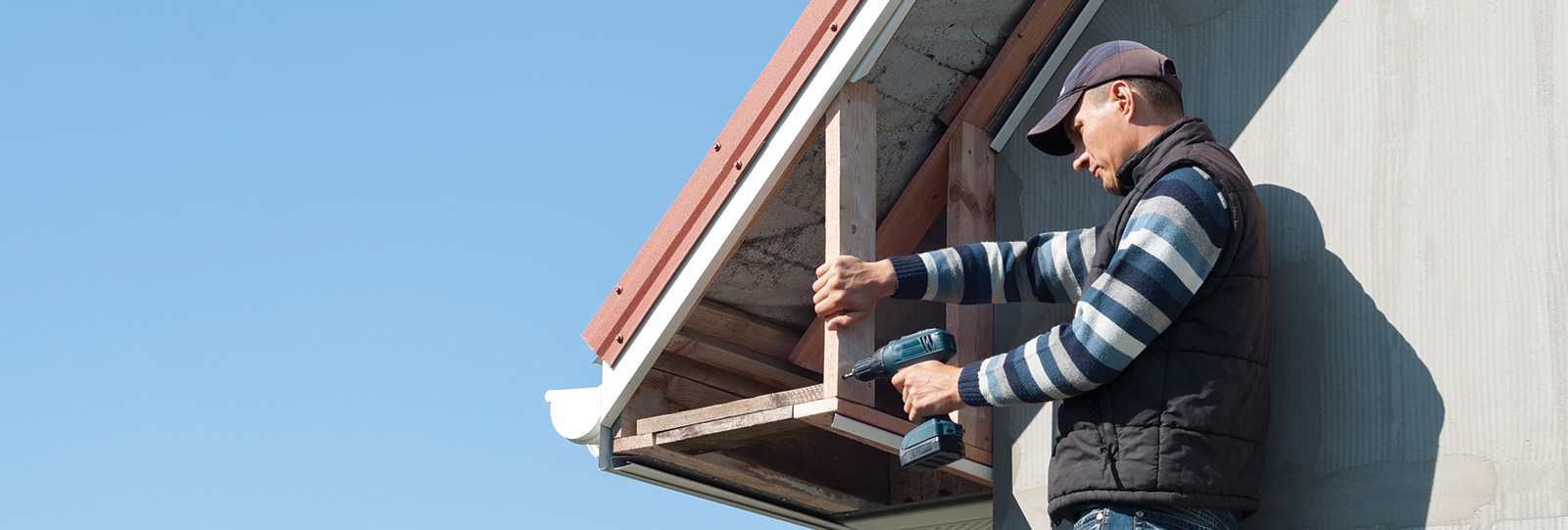 A Rümi home exterior pro repairs soffit and fascia on a roof.