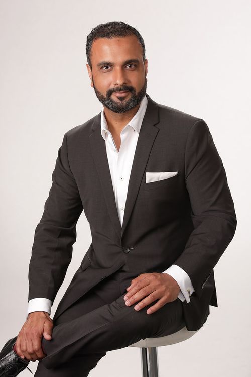 Professional portrait of Harry Gakhal, showcasing his confidence and expertise in the real estate industry, wearing a tailored grey suit