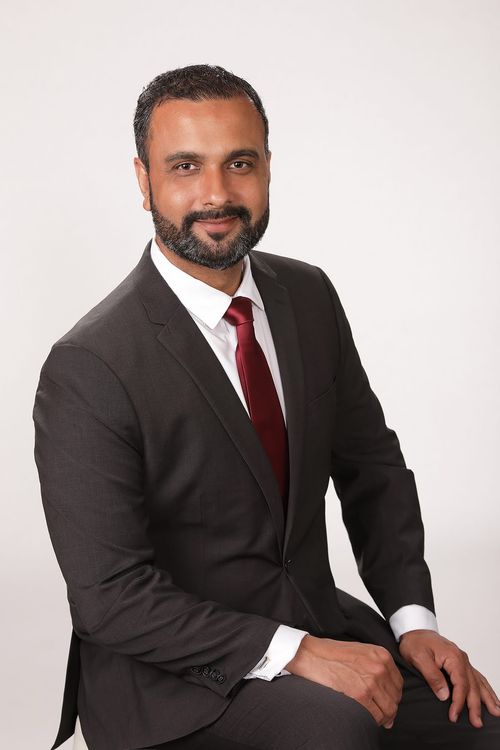 Harry Gakhal, real estate investor and consultant, in professional attire with a maroon tie.