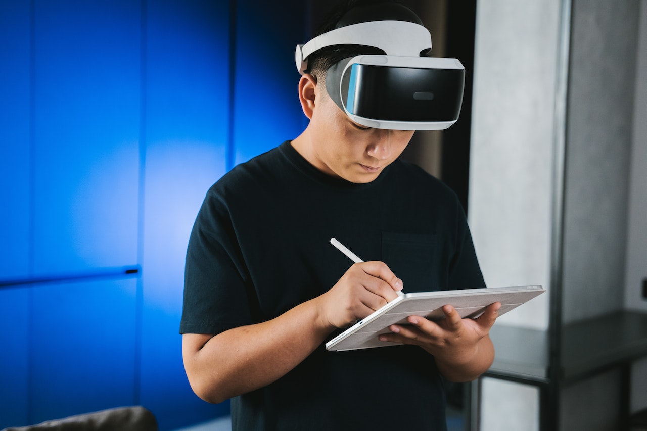 Engineer who is wearing a VR headset lifted up slightly as he jots down notes on an iPad