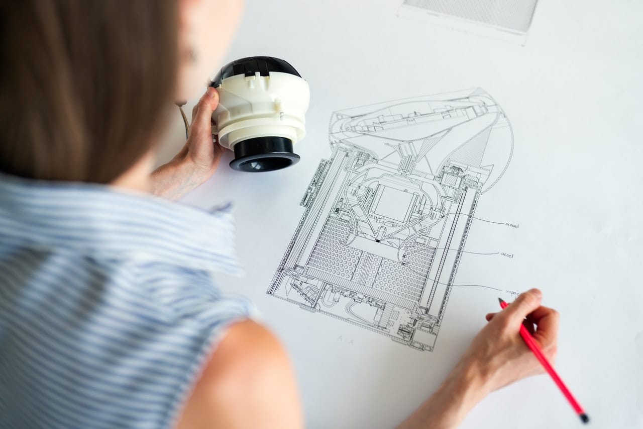 Female sketching out mechanical part with paper and pencil