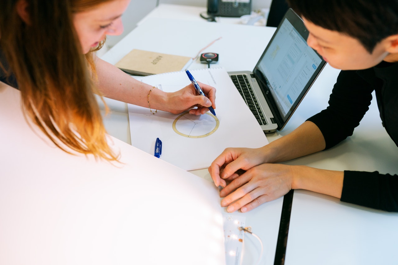 Two people working on a mechanical sketch together at a table