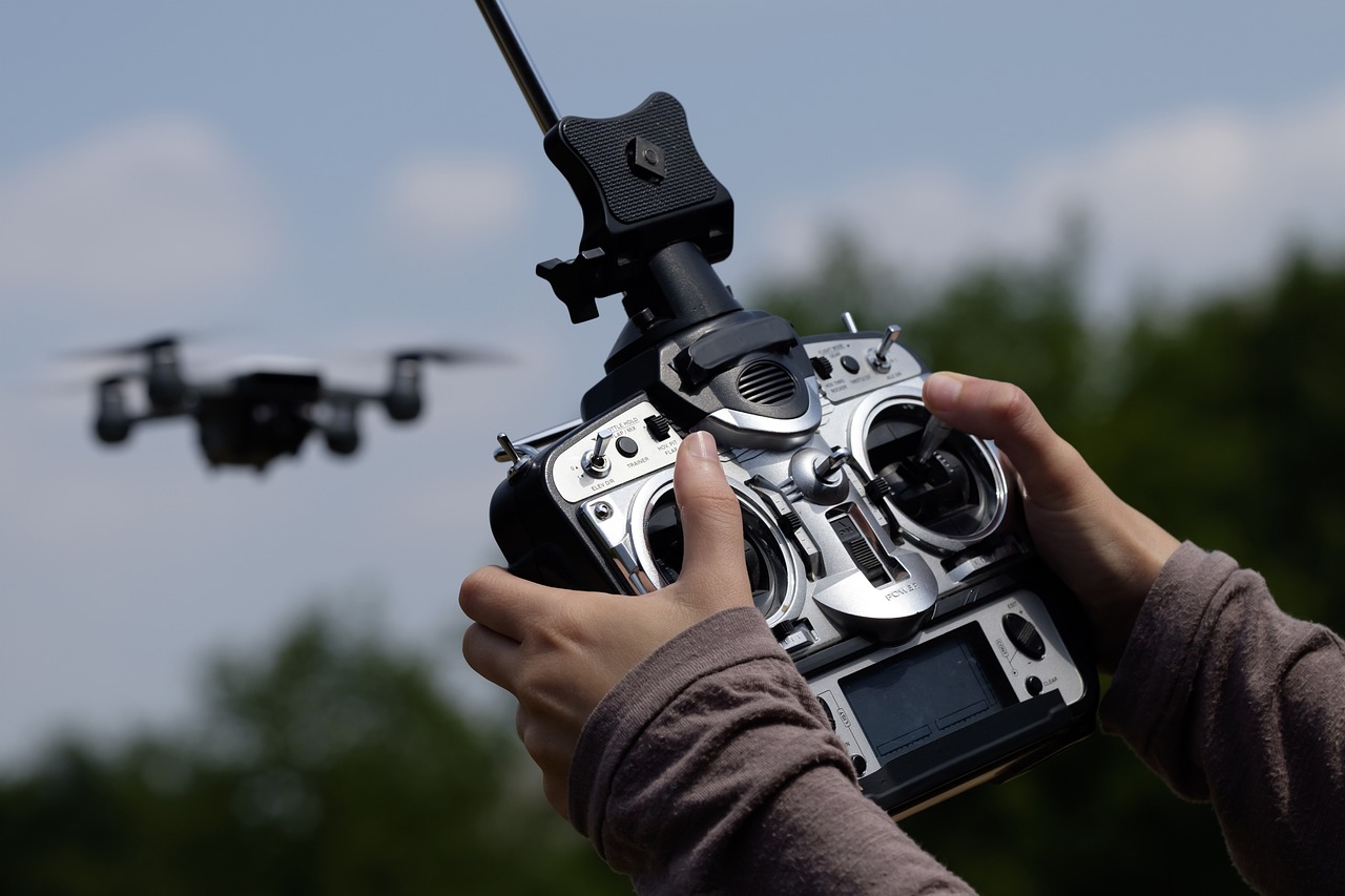 Hands and drone controller controlling drone flying in the background