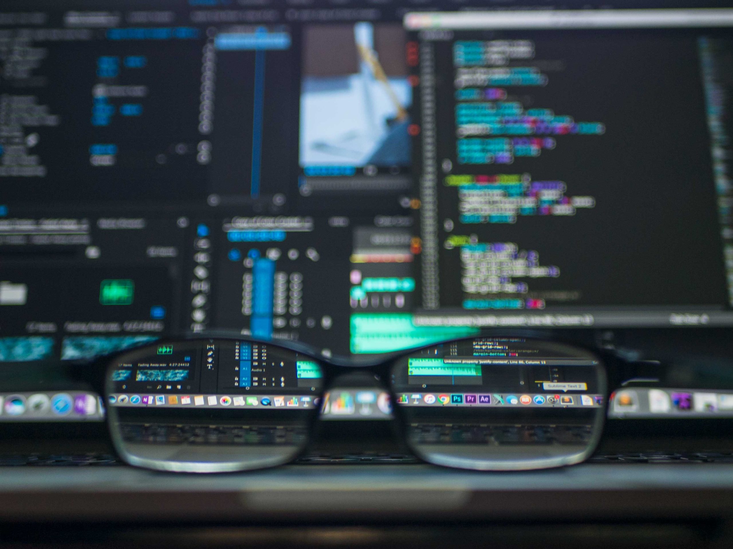 Eyeglasses on desk in front of firmware programming on computer screen