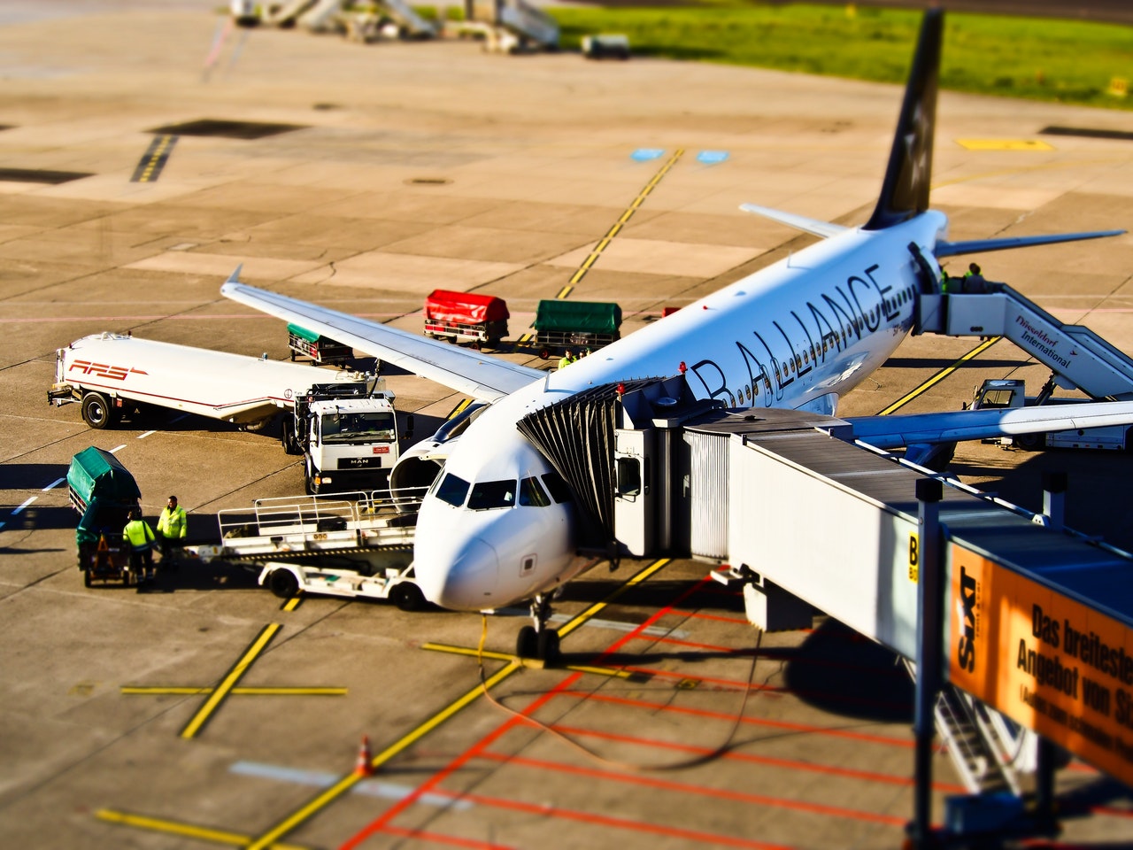 Commercial airplane at airport gate with gangway rolled up to it as it is loading up with passengers and baggage