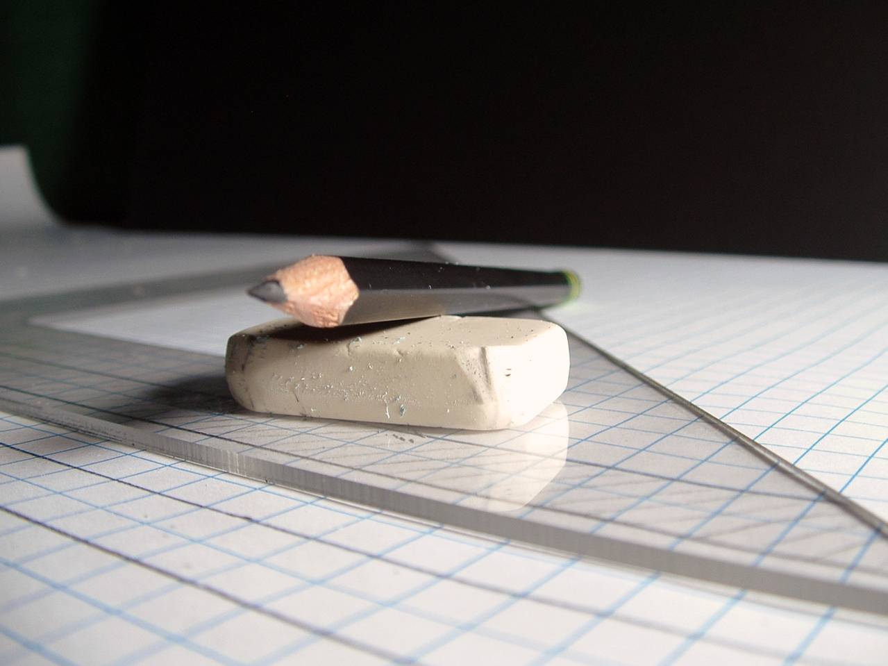 Pencil, eraser, triangle and paper sitting on drafting table