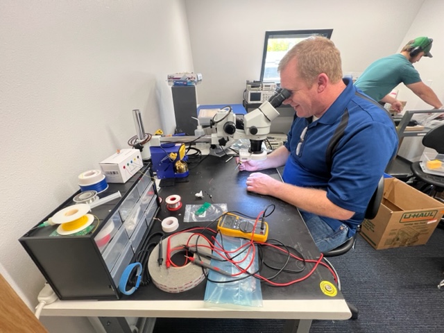 Engineer in electronics lab looking through microscope