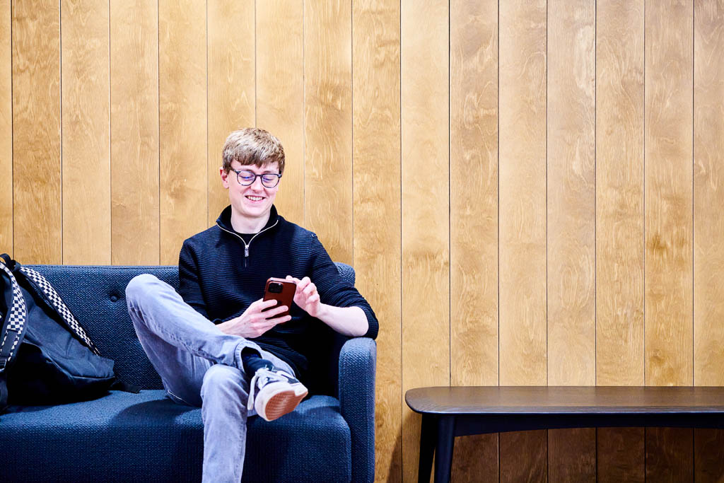 Author of the blog, Jake Bazin sitting on a sofa, relaxing with his phone.