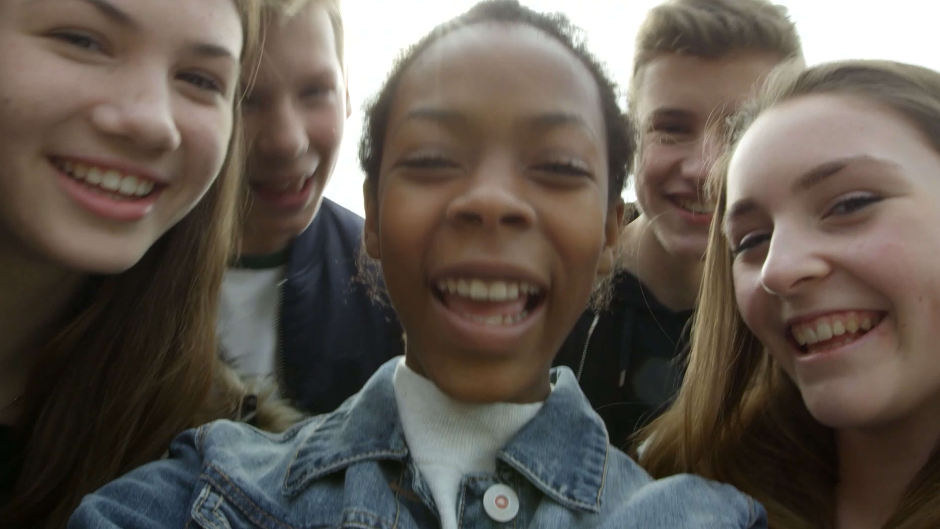 Teenagers circling around the camera and laughing