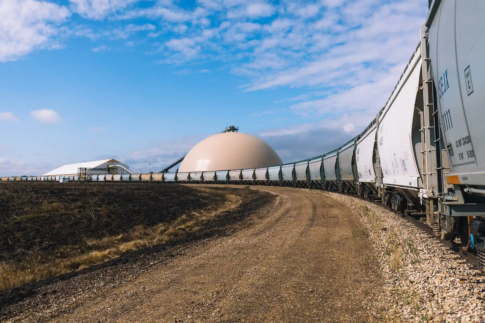 Train cars extending into the horizon with a silo in the background